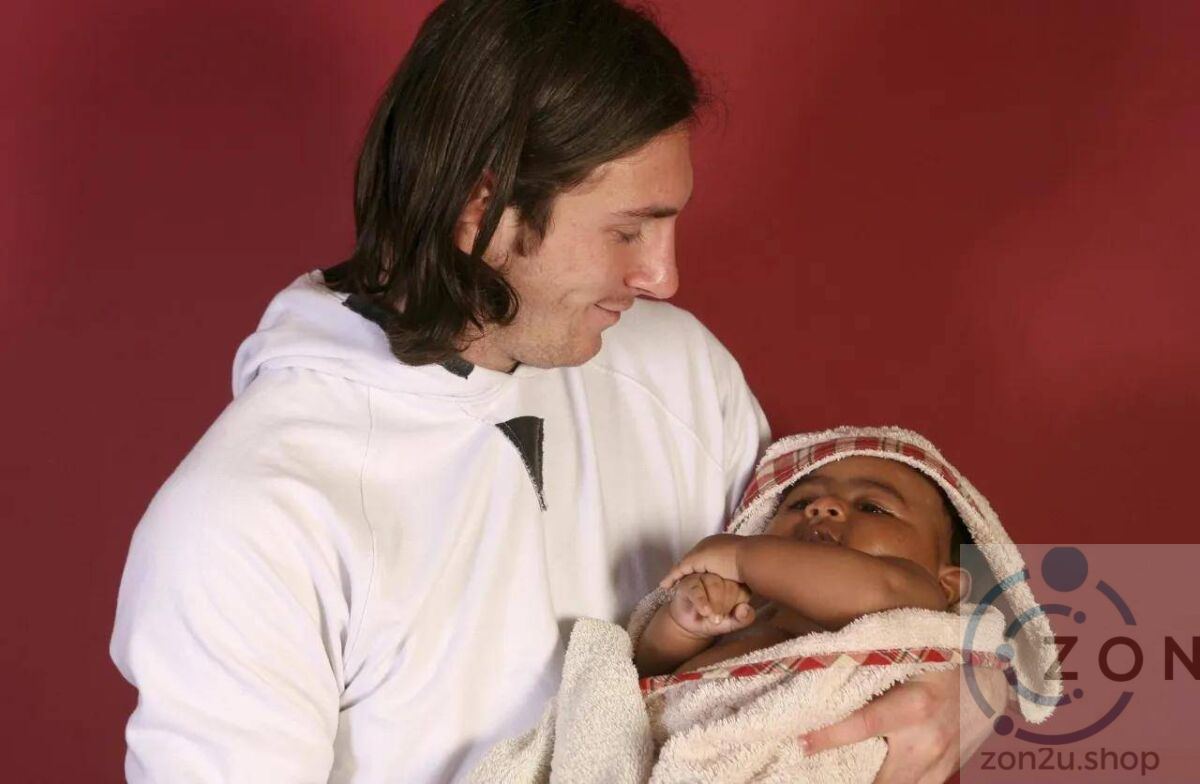 A man in a white hoodie holding a baby wrapped in a towel