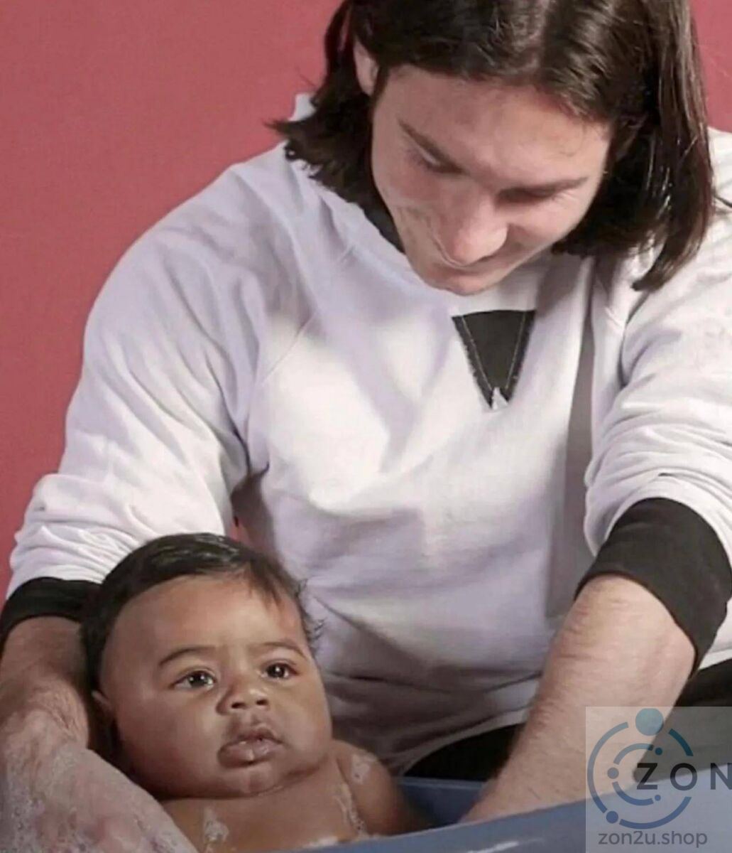 A man looks down at a baby in a bathtub