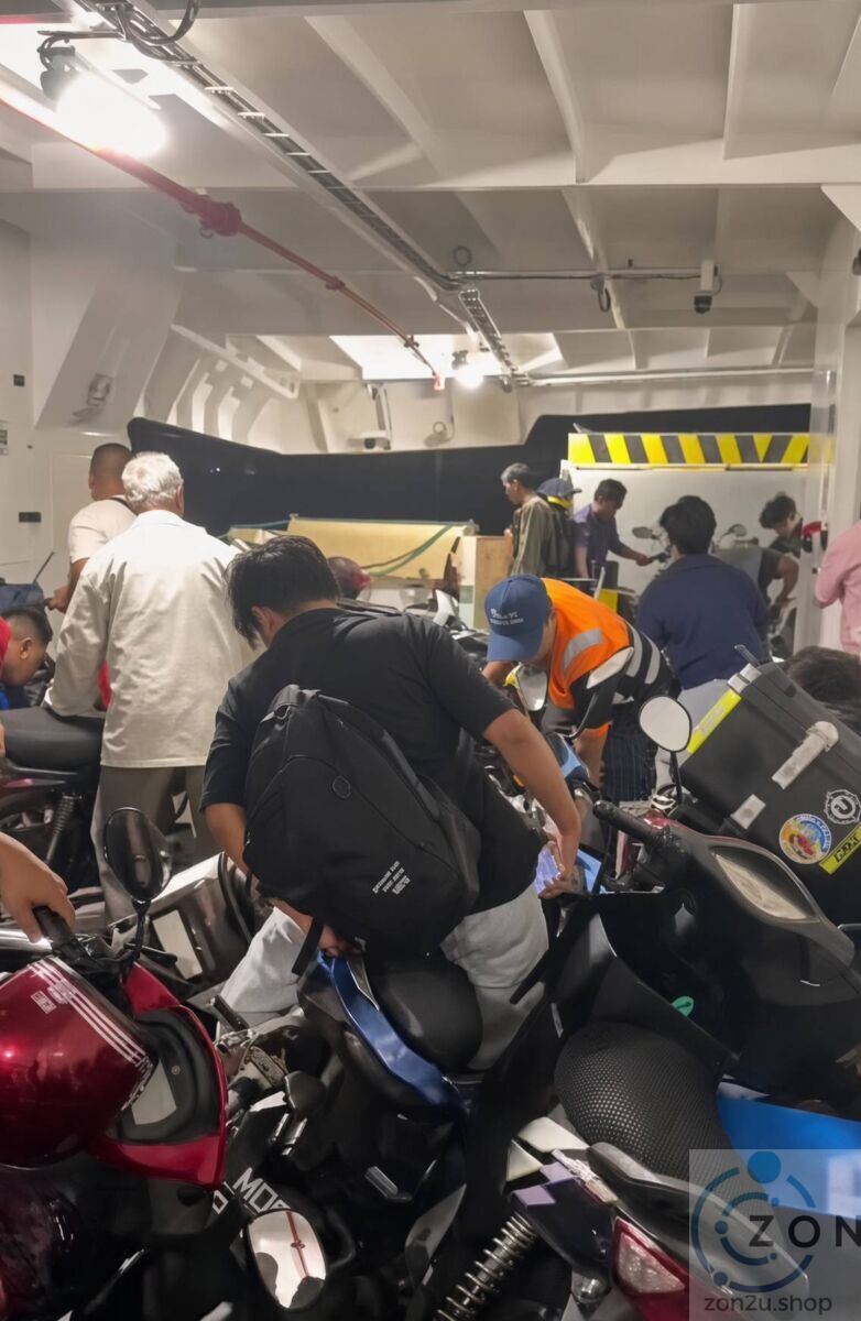 Passengers and staff arranging tightly parked motorcycles on the lower deck of a ferry